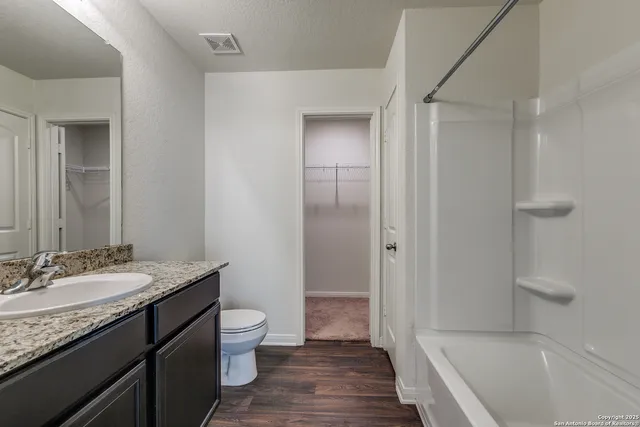 a bathroom with a granite countertop sink a toilet and shower