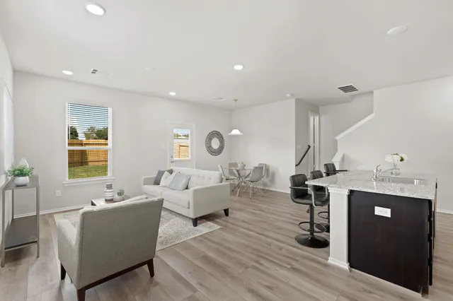 a living room with furniture kitchen view and a wooden floor