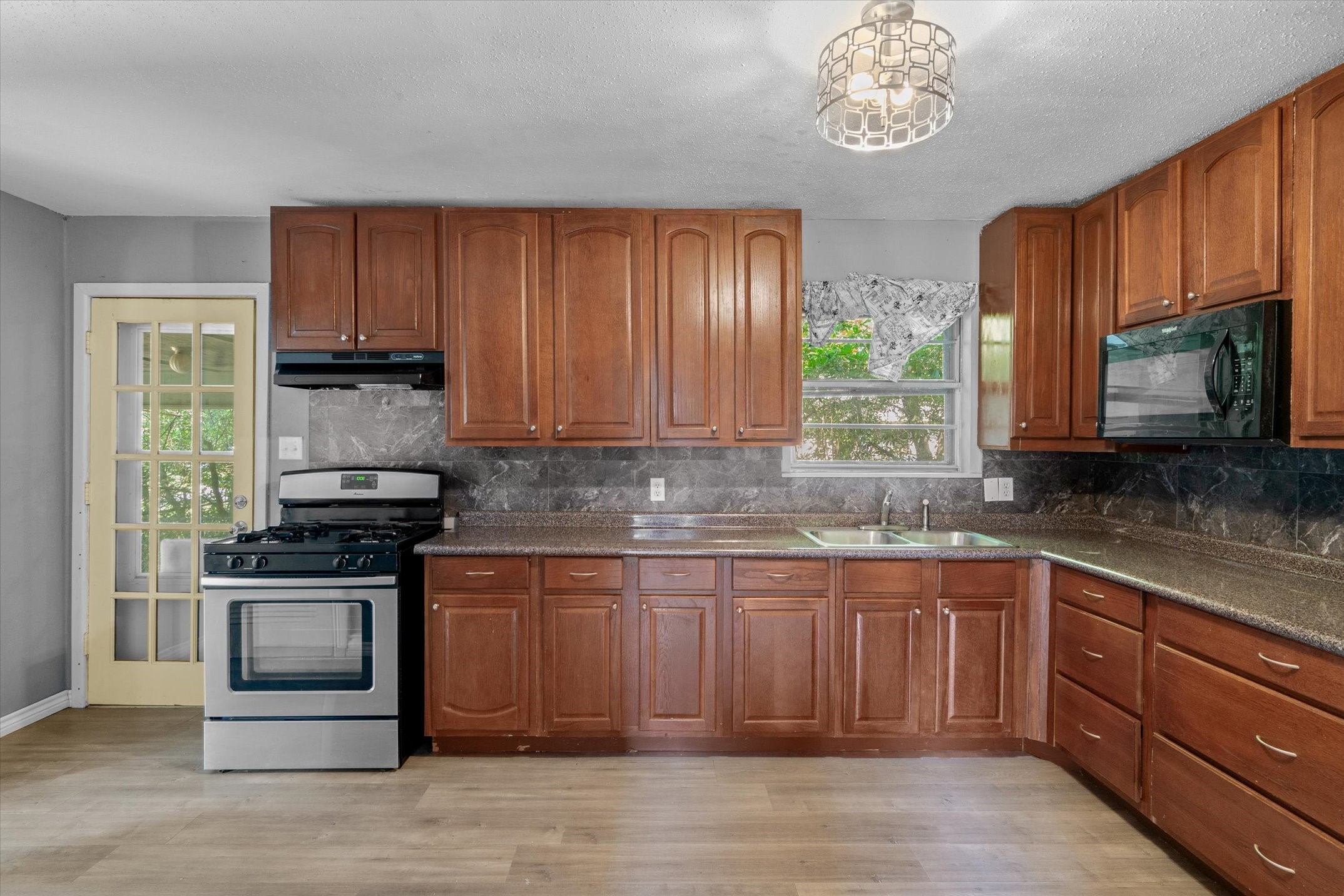 410 Williams Street Athens, TX 75751 - Photo 13 of 30 a kitchen with stainless steel appliances granite countertop a stove a sink dishwasher and a microwave oven with wooden floor