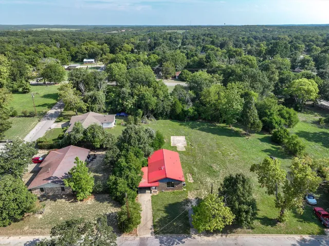 an aerial view of residential house with outdoor space and trees all around