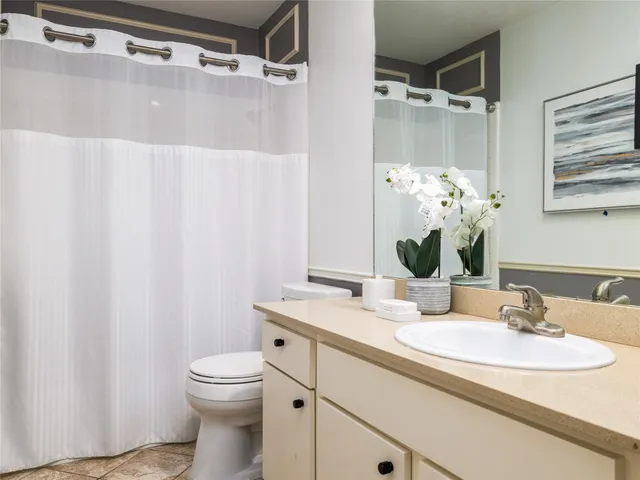 a bathroom with a granite countertop sink a toilet and a mirror