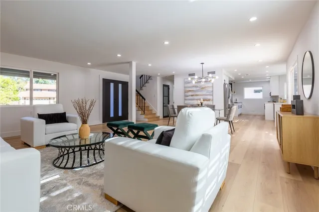 a living room with furniture kitchen view and a large window
