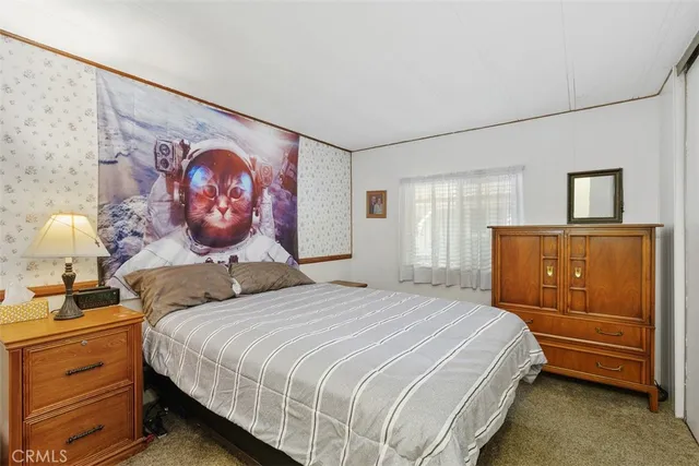 a bedroom with a bed and a lamp on the dresser