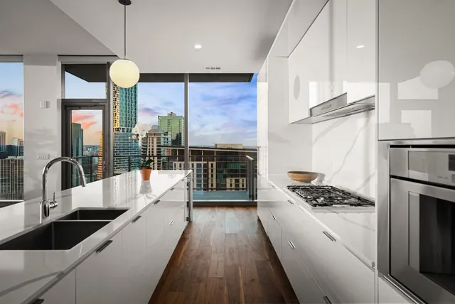 a large kitchen with stainless steel appliances a large counter top a stove a chimney a sink and a large window