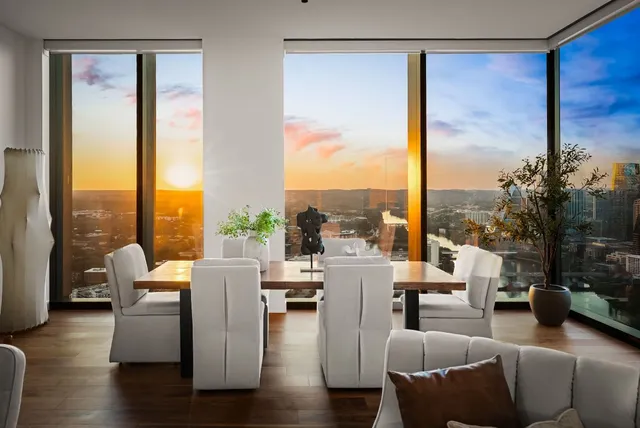 a living room with furniture large windows and wooden floor