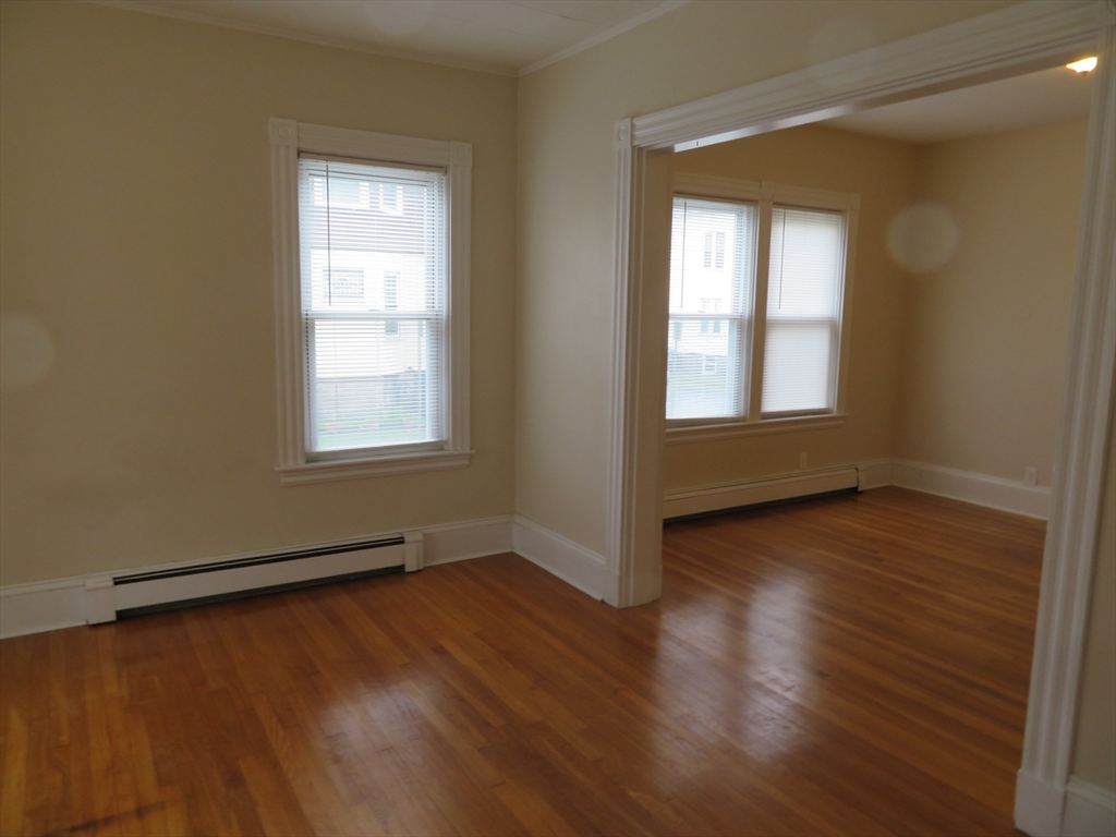 685 Cottage, Unit 1 New Bedford, MA 02745 - Photo 2 of 13 an empty room with wooden floor and windows