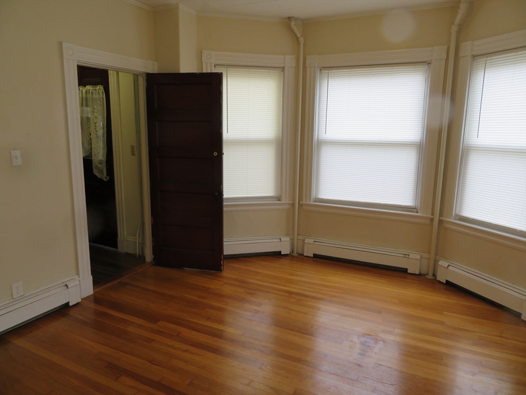 685 Cottage, Unit 1 New Bedford, MA 02745 - Photo 3 of 13 an empty room with wooden floor and windows