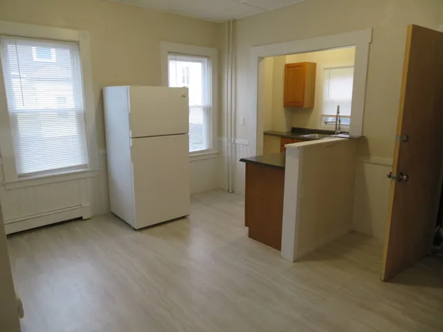a view of a kitchen with refrigerator and wooden floor