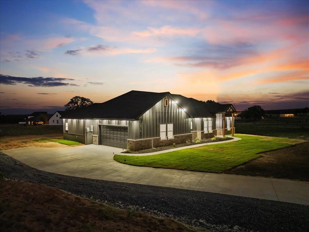 3028 West Frk Way Springtown, TX 76082 - Photo 2 of 24 Modern farmhouse at dusk with siding, brick accents, bright exterior lighting, and great curb appeal.