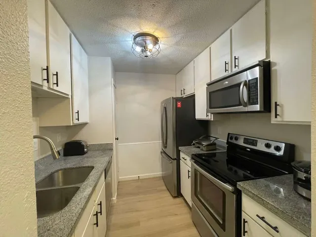 a kitchen with stainless steel appliances granite countertop a sink stove and microwave