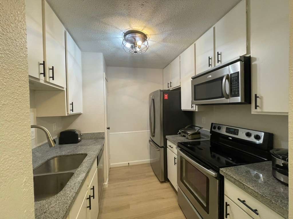 7950 North Stadium Drive, Unit 172 Houston, TX 77030 - Photo 7 of 13 a kitchen with stainless steel appliances granite countertop a sink stove and microwave