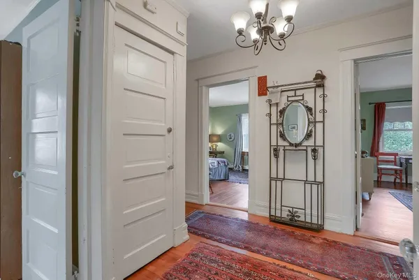a view of a hallway with wooden floor and a chandelier