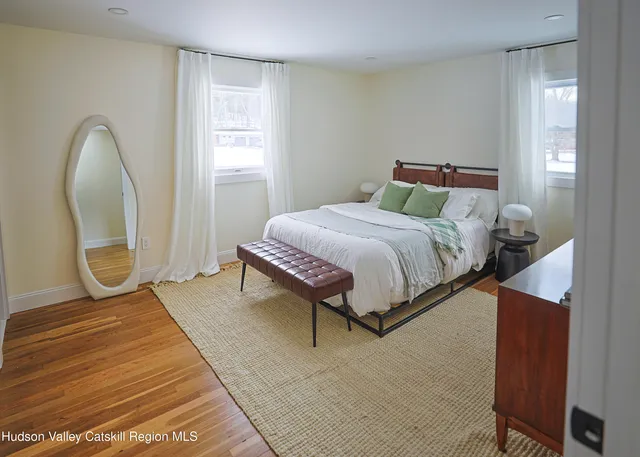 a bedroom with a bed a mirror and a window