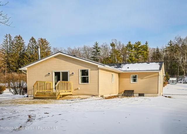 a view of a white house with a yard and large trees