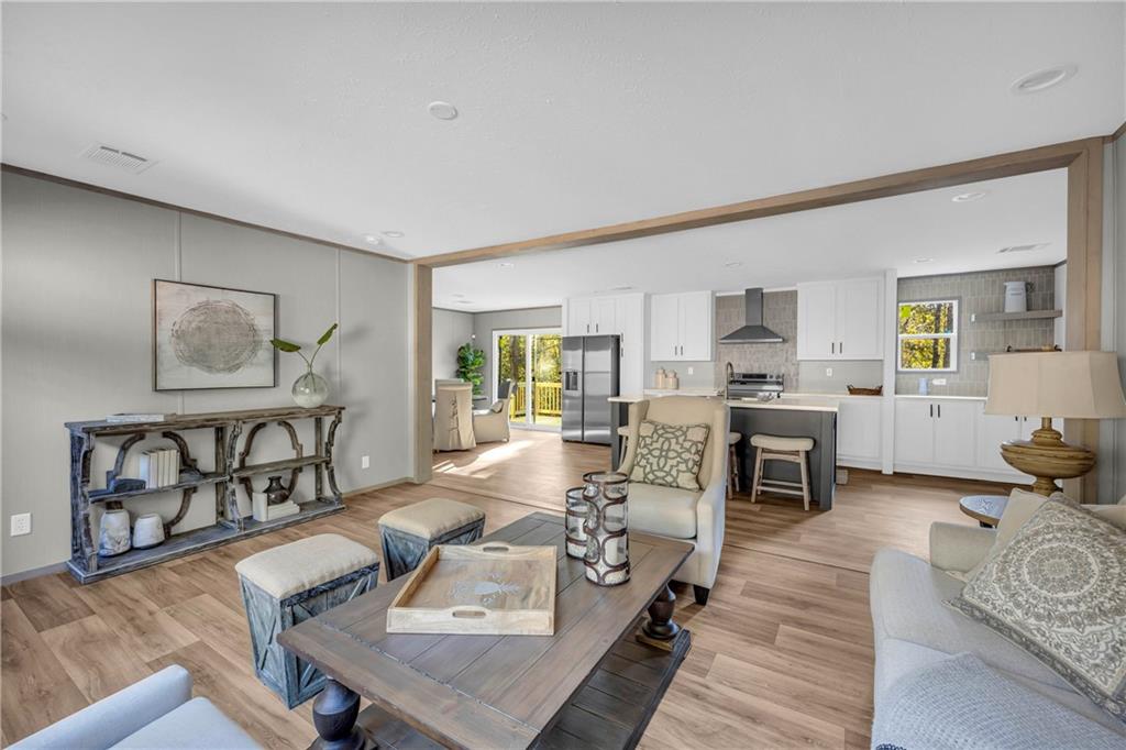 a living room with furniture kitchen view and a wooden floor