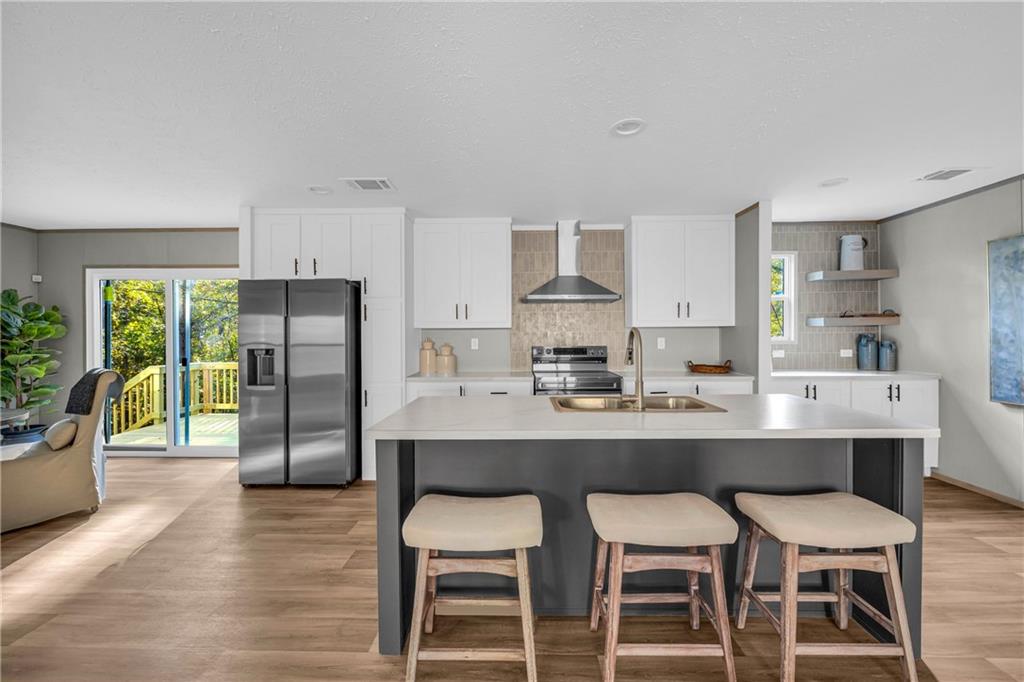 a kitchen with stainless steel appliances a dining table chairs refrigerator and sink