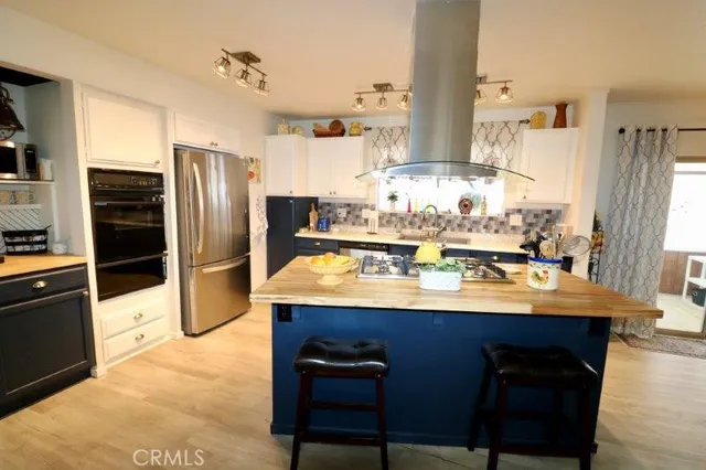 a kitchen with stainless steel appliances kitchen island granite countertop a stove a sink a refrigerator and cabinets