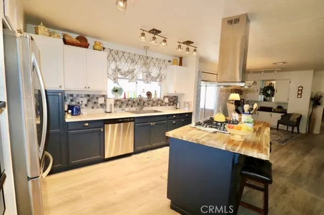 a living room with stainless steel appliances furniture a rug and a kitchen view