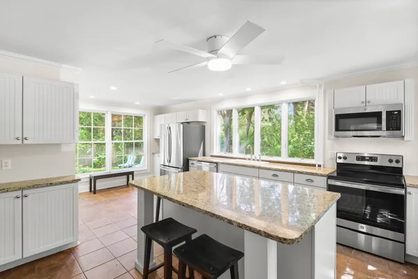 a kitchen with granite countertop a stove a sink and a refrigerator