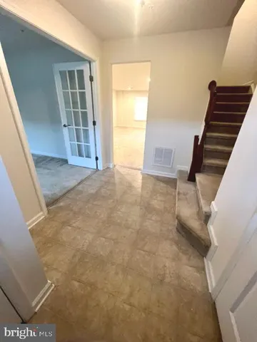 a view of an empty room with wooden floor and stairs