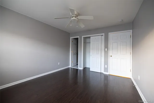 a view of an empty room with a ceiling fan and wooden floor