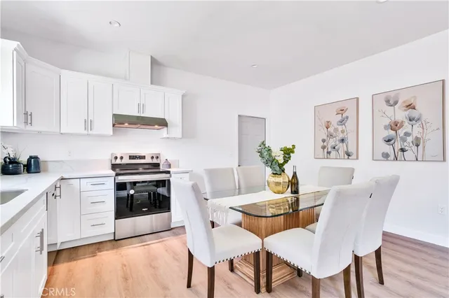 a kitchen with stainless steel appliances a dining table chairs and a refrigerator
