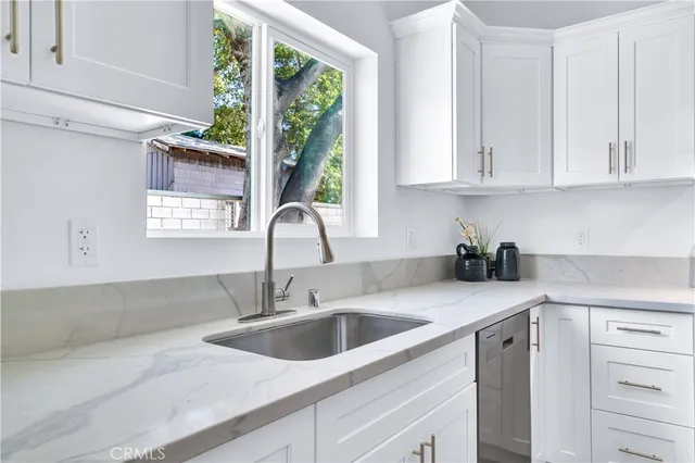 a kitchen with stainless steel appliances granite countertop a sink a window and cabinets
