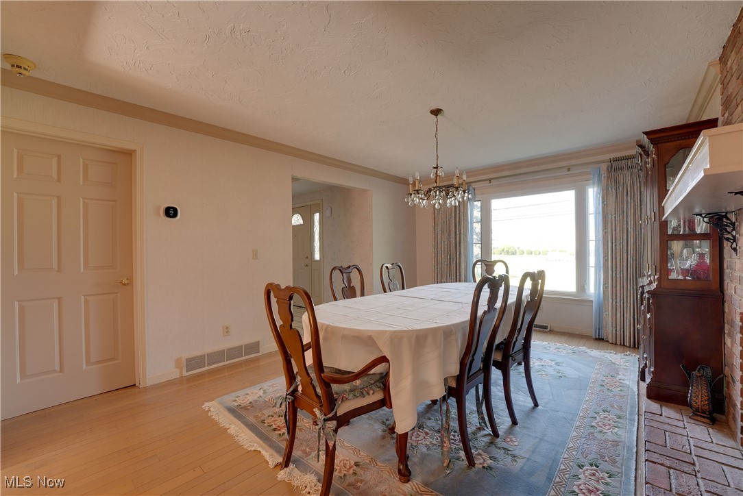 4939 Shankland Road Willoughby, OH 44094 - Photo 9 of 24 Dining area with a chandelier, a textured ceiling, and light wood-style flooring