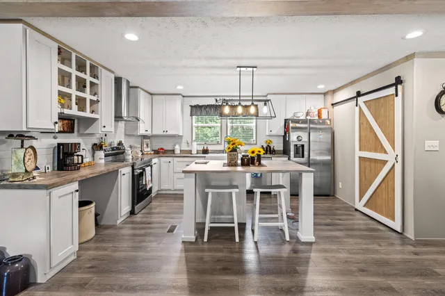 a kitchen with stainless steel appliances a dining table chairs and wooden floor