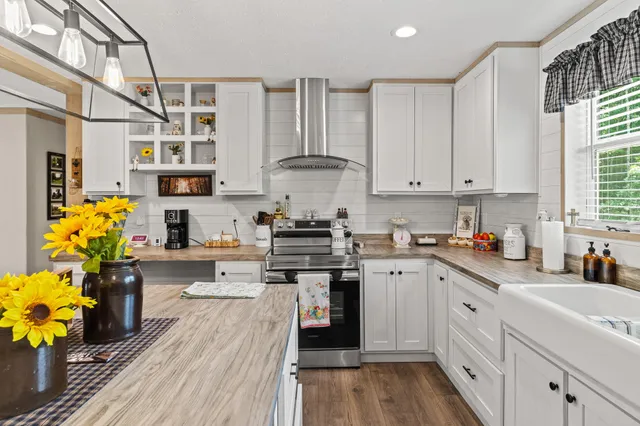 a kitchen with stainless steel appliances granite countertop a stove a sink and white cabinets