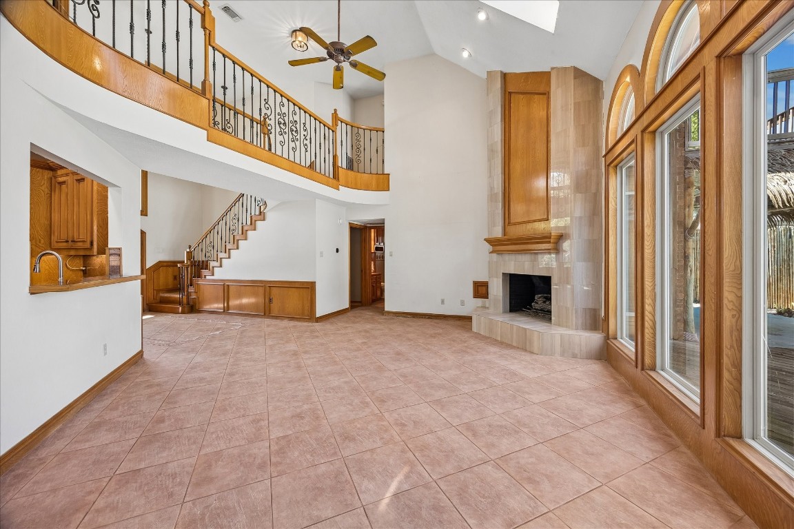 1835 Raintree Circle Seabrook, TX 77586 - Photo 12 of 50 This spacious living room features high ceilings, a grand staircase, and large arched windows for abundant natural light. The open layout includes a cozy fireplace and elegant railing on the upper level, enhancing the home's airy and inviting atmosphere.