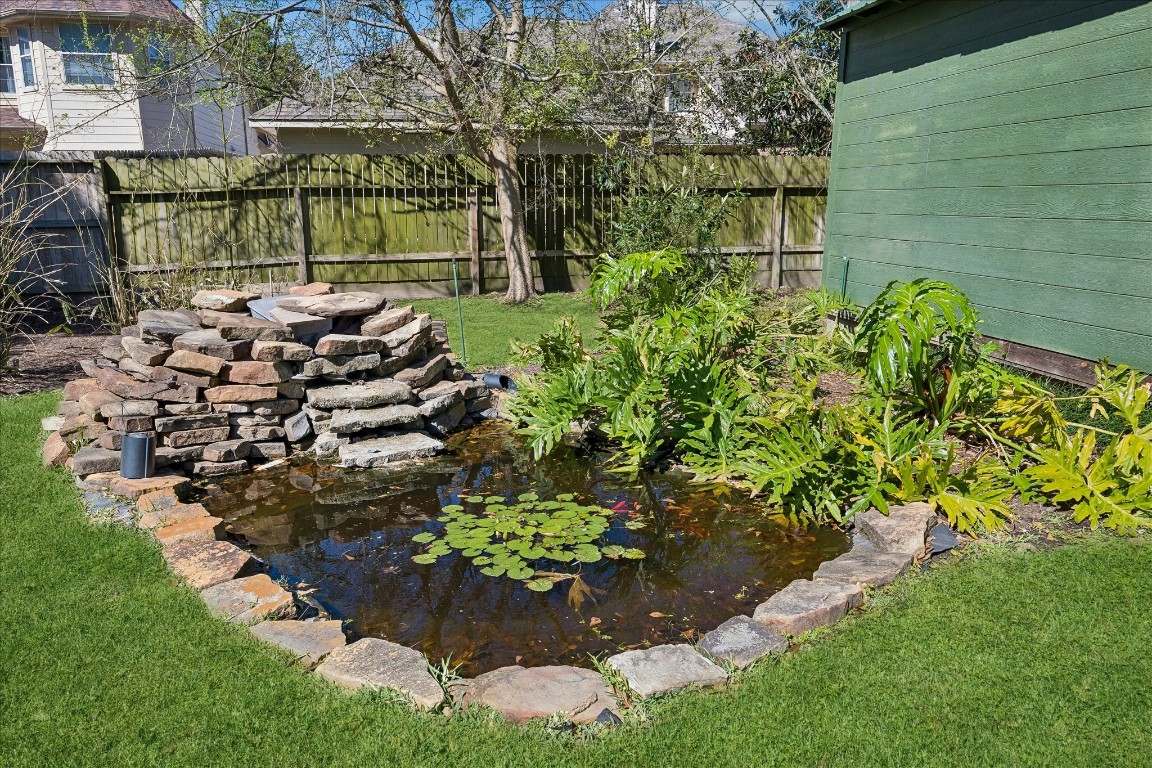 1835 Raintree Circle Seabrook, TX 77586 - Photo 37 of 50 Charming backyard with a small pond, surrounded by lush greenery and a rock waterfall feature. Perfect for relaxation and enjoying nature.