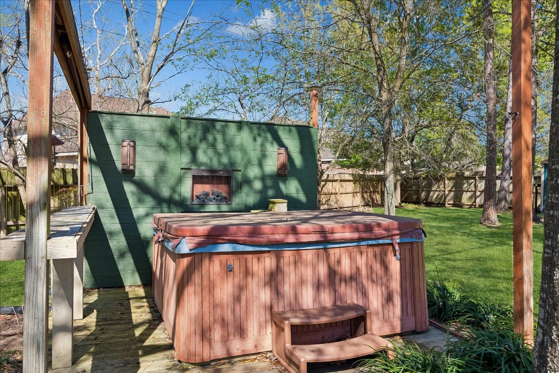 1835 Raintree Circle Seabrook, TX 77586 - Photo 39 of 50 This backyard features a wooden hot tub with a small step, set on a deck. It's surrounded by a privacy screen and lush green grass, creating a relaxing outdoor space.