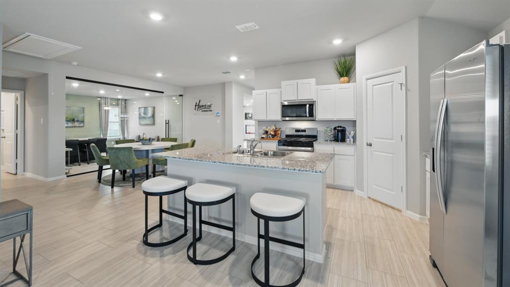 1645 Tin Roof Road Krum, TX 76249 - Photo 1 of 36 a kitchen with stainless steel appliances a dining table chairs refrigerator and sink
