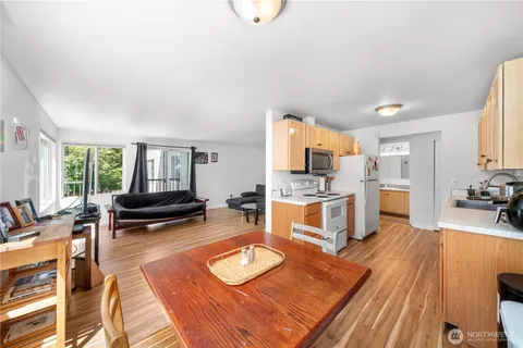 a living room with furniture a rug kitchen view and a large window