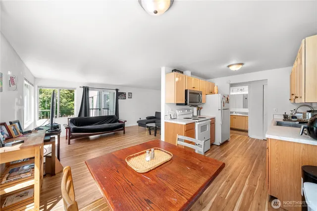a living room with furniture a rug kitchen view and a large window