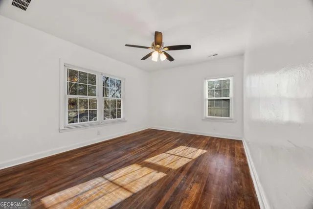 a view of empty room with wooden floor and fan
