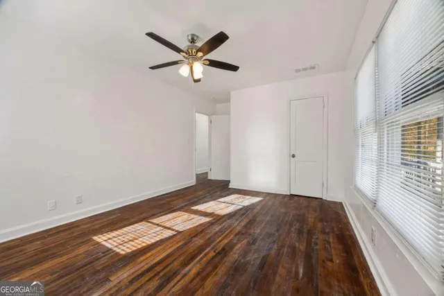 a view of a big room with wooden floor and windows