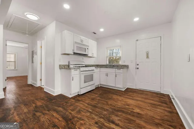 a kitchen with stainless steel appliances a white cabinets and wooden floor