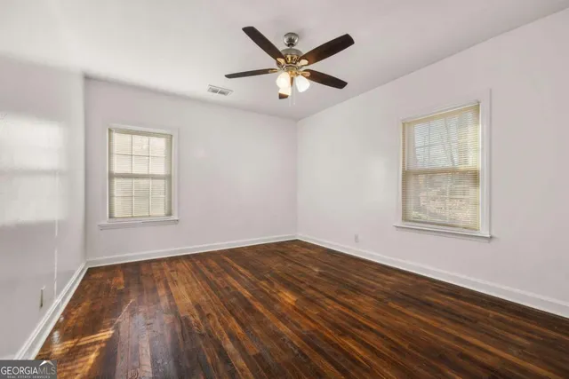 a view of empty room with wooden floor and fan