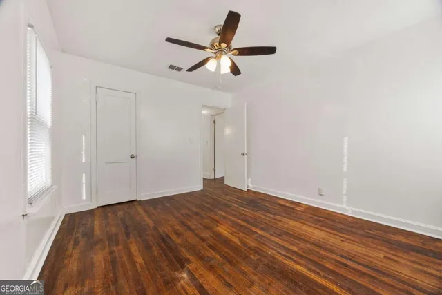 a view of empty room with wooden floor and fan