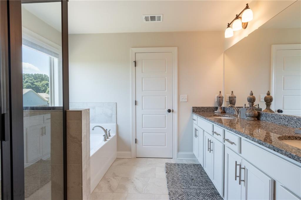 560 Calgary Downs Drive Winder, GA 30680 - Photo 26 of 37 a bathroom with a granite countertop sink a mirror and a shower