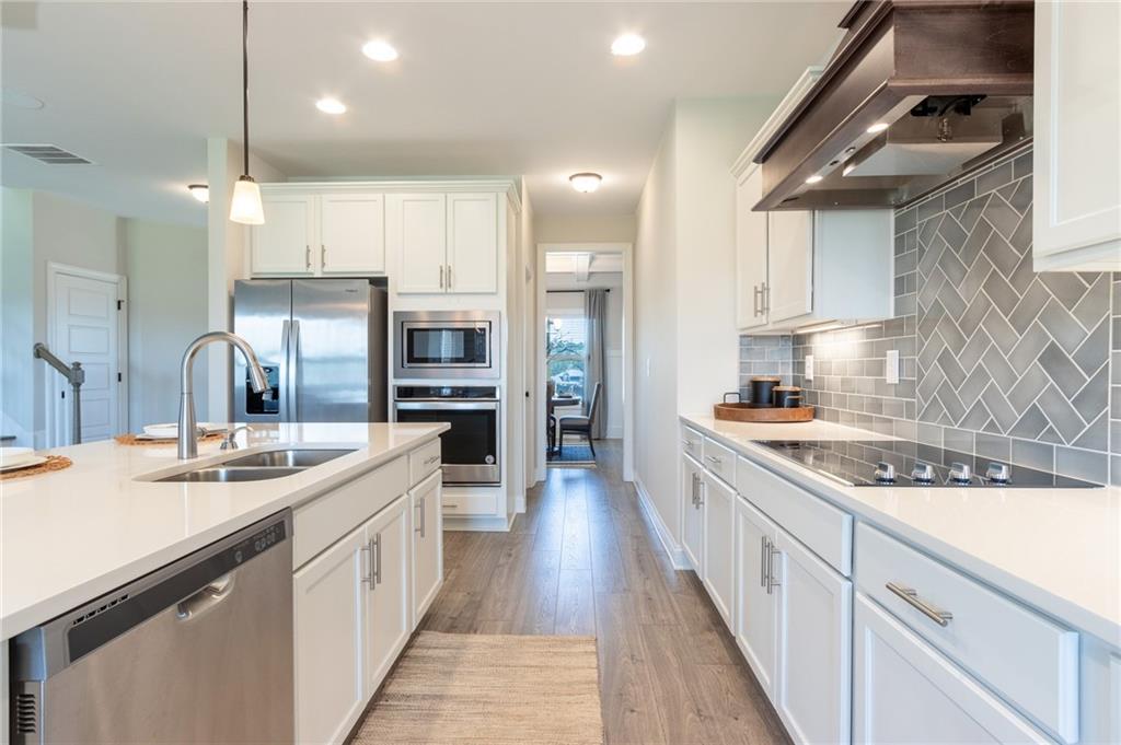 560 Calgary Downs Drive Winder, GA 30680 - Photo 9 of 37 a large kitchen with stainless steel appliances kitchen island granite countertop a sink a stove and cabinets