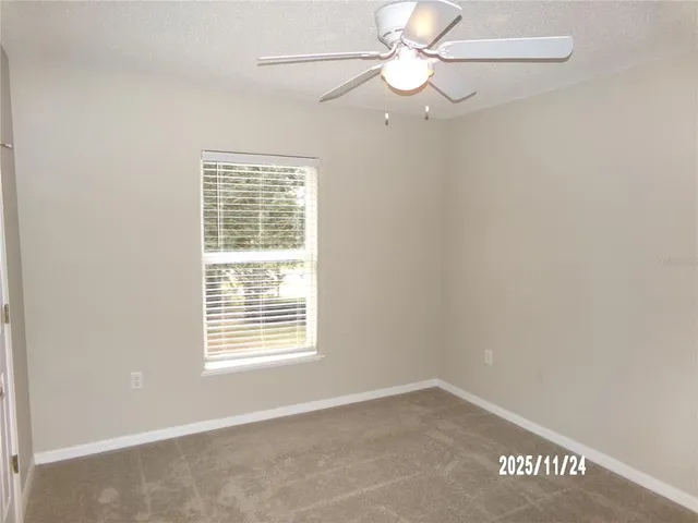 an empty room with a window and a fan