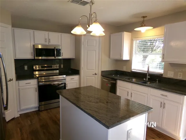 a kitchen with granite countertop a sink a counter top space appliances and cabinets