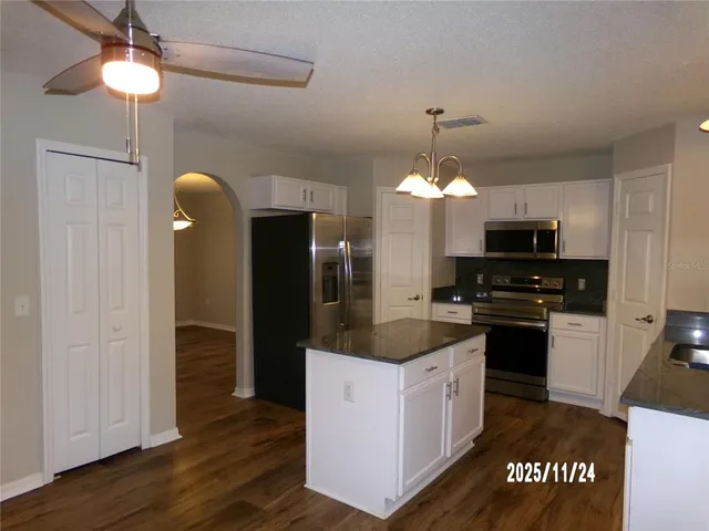 a kitchen with a chandelier stainless steel appliances and cabinets