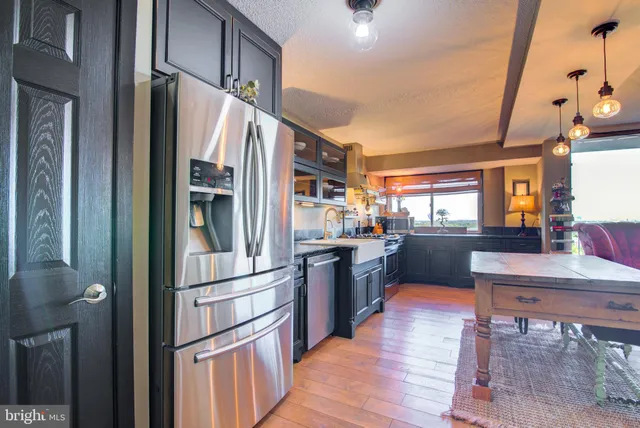 a kitchen with granite countertop a refrigerator stove and wooden floor