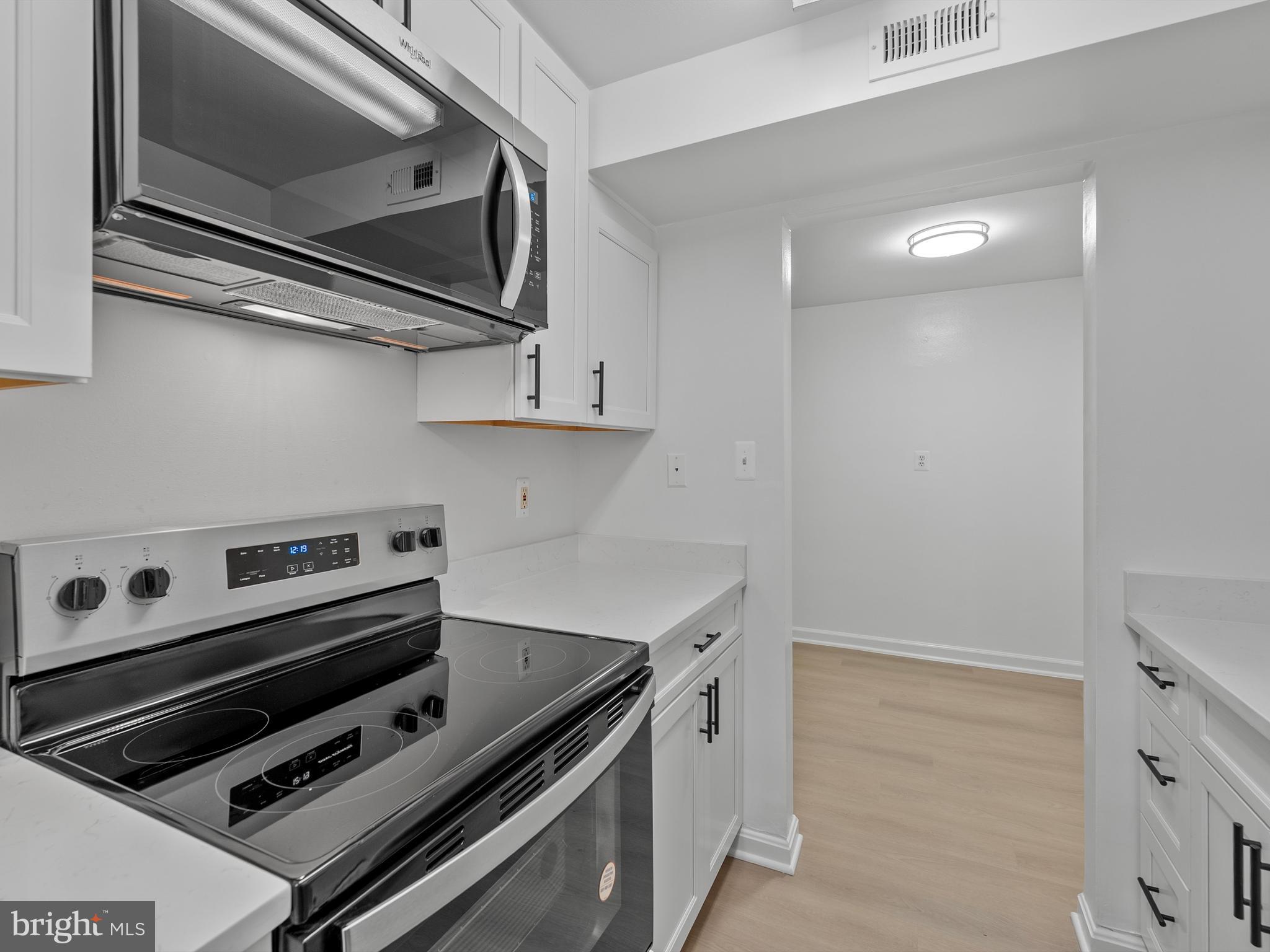 708 South Arlington Mill Drive, Unit 104 Arlington, VA 22204 - Photo 10 of 24 a kitchen with a stove and a microwave