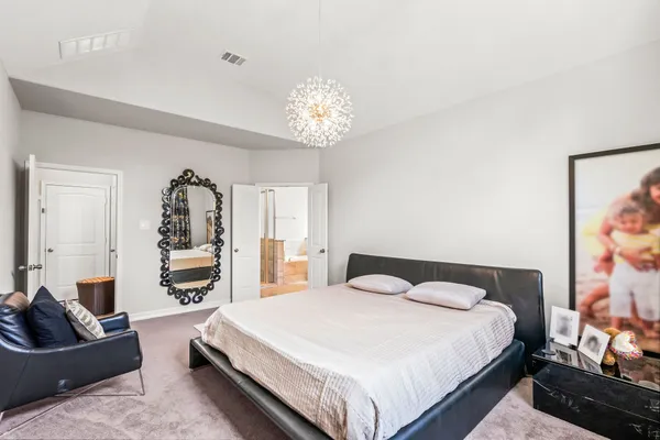a bedroom with a large bed and a chandelier