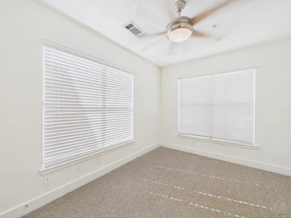 an empty room with a window and ceiling fan
